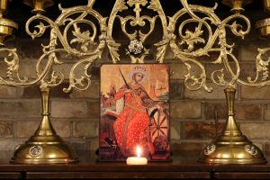 Image of icon and candelabra with lit candle.